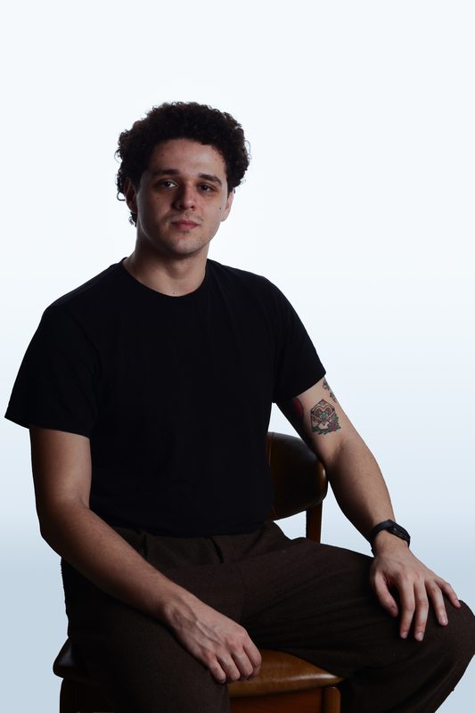 Retrato do fotógrafo sentado em uma cadeira de madeira, fundo claro